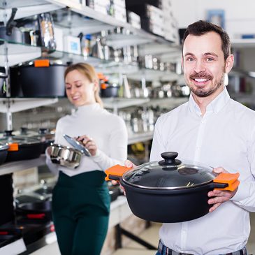 Male salesman helps to choose new kitchen utensils for customers in the store