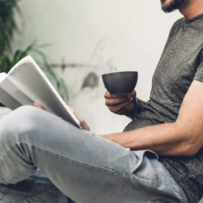 Handsome hipster man relaxing read the paper book work study and looking at page magazine while sitting on chair in cafe and restaurant