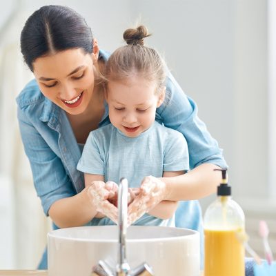 A cute little girl and her mother are washing their hands. Protection against infections and viruses.